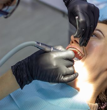 Beautiful woman in dental chair during procedure of installing braces to upper and lower teeth. Dentist and assistant working together, dental tools in their hands. Top view. Concept of dentistry