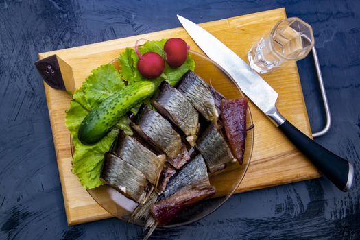 cucumber and chopped smoked herring on a plate stands next to a shot of vodka