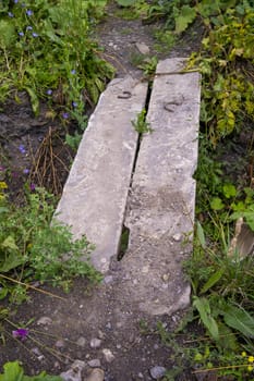 bridge of two concrete blocks across a shallow ditch