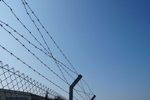barbed wire fence against blue sky, copy space