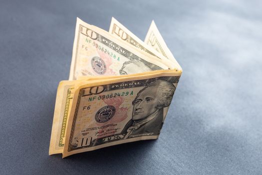 40 dollars on abstract black surface - 4 of 10 dollar banknotes bent and standing. Close-up with selective focus and blur.