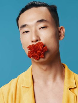 A man in a yellow coat with a red flower in his mouth on a blue background . High quality photo