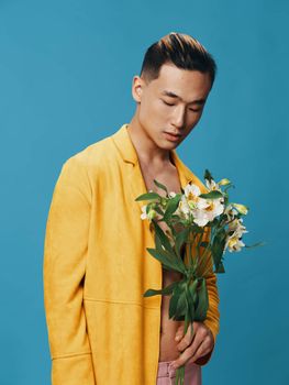 A cute guy of Asian appearance holding a bouquet of white flowers portrait cropped view. High quality photo