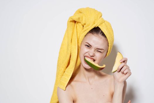 Woman with bare shoulders yellow towel on head mango exotic vitamins fruits. High quality photo
