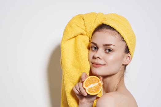 Pretty woman you yellow towel on head oranges citrus clean skin light background. High quality photo