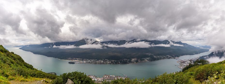 Panoramic view of port of Gastineau Channel, port of Juneau and mountains covered with clouds from the top of mountain Roberts in Alaska.