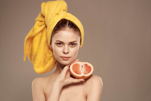 Beautiful woman with a towel on her head bared shoulders grapefruit Skin care. High quality photo