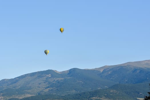 Colorful hot air balloons flying over the mountain in Puig Cerda, Spain.