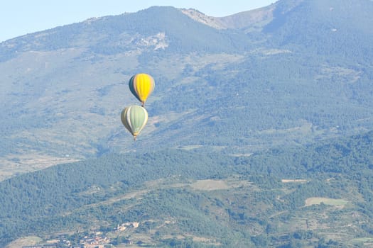 Colorful hot air balloons flying over the mountain in Puig Cerda, Spain.