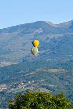 Colorful hot air balloons flying over the mountain in Puig Cerda, Spain.