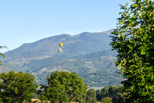 Colorful hot air balloons flying over the mountain in Puig Cerda, Spain.