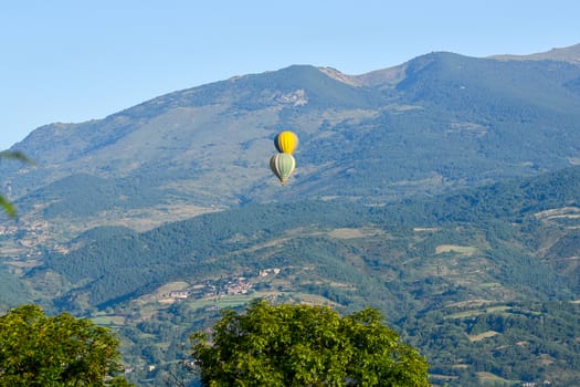 Colorful hot air balloons flying over the mountain in Puig Cerda, Spain.