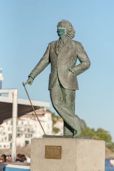 Cadaques, Spain : 07 JULY 2020 : Salvador Dali Statue in the beach and houses of the village of Cadaques, Spain in summer on 07 july 2020.