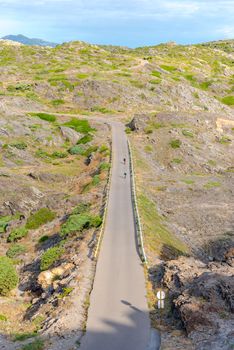 Parc Natural Cap de Creus, Spain :  8 july 2020 : Two cyclists in  Cap de Creus, natural park. Eastern point of Spain, Girona province, Catalonia. Famous tourist destination in Costa Brava. Sunny summer day with blue sky and clouds