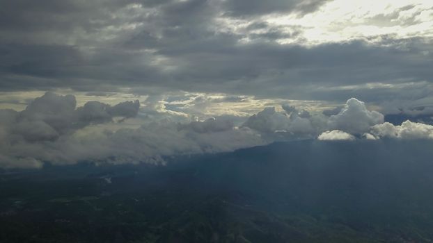 volcano with cloudy clear sky. Mount Merapi in Indonesia. Cloudy sky with a volcano in the background. Clouds around the top of the mountain. The sun's rays shine through the clouds.