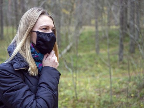 Beautiful european Women Wearing Protective Mask Outside Pretty young girl in medical black face mask in a forest. covid19 concept. modern reality. copy space. 2020, allergy. Autumn season. Copy space