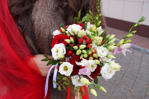 bride in a red dress holds a wedding bouquet, close-up