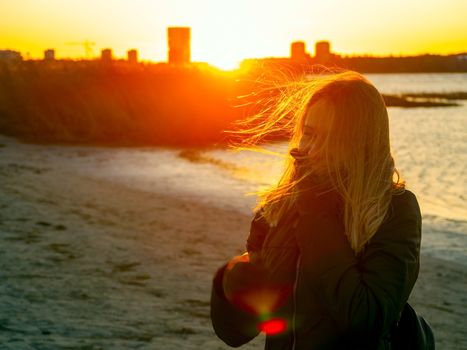 Silhouette of a lonely woman watching sunset in autumn. downtown buildings silhouettes. Nature Orange sea sunset in the city landscape beautiful landscape of Tallinn skyline Panoramic view on beach