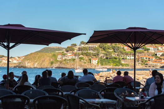 Coliure, France :  2020 june 22 :  Restaurant in Old town of Collioure, France, a popular resort town on Mediterranean sea, panoramic view with the Royal castle in sunrise light