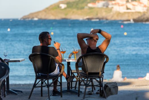 Coliure, France :  2020 june 22 :  Restaurant in Old town of Collioure, France, a popular resort town on Mediterranean sea, panoramic view with the Royal castle in sunrise light