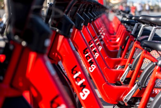 Barcelona, Spain - June 26, 2020: Bright red bicycles available for rent parked in a row at La Barceloneta. Concept of environmentally sustainable transport. Bike rental service Bicing.