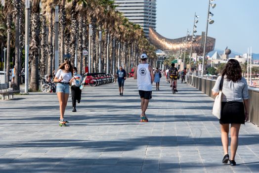 BARCELONA - JUNE 26, 2020: People Wal k Barceloneta Beach with Frank Gehry's Peix d'Or (Whale Sculpture) in summer after COVID 19 on June 26, 2020 in Barcelona, ​​Spain.