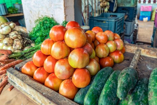 Neat group of red tomatoes and cucumbers at a stall