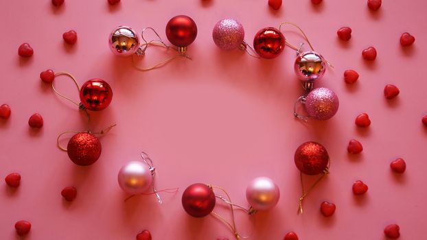 Festive frame made of christmas balls on pink table top view. Fashion background. Flat lay. Party mockup.