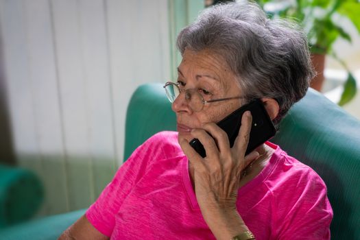 Senior woman with eyeglasses sitting, using a cell phone