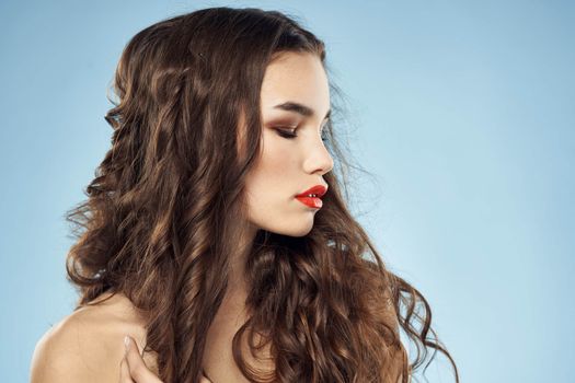 Brunette naked shoulders red lips fashionable hairstyle blue background. High quality photo