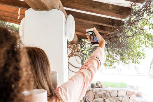 Mixed race female couple in pajama make self portrait with smartphone in the garden just woken up - Homosexual women couple in vacation using social network to sharing their diversity - Focus on phone