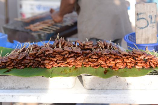 Grilled Pork, also known as Pork BBQ, is a famous Thai street food. Stacked on the banana leaf Is on a blurred background