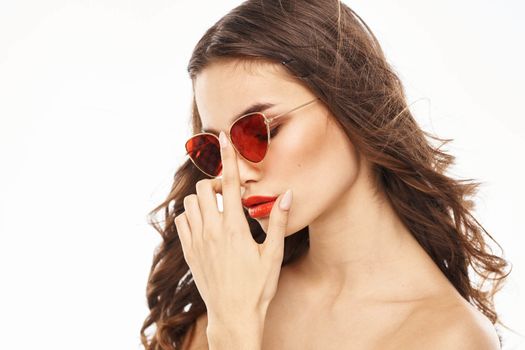 Portrait of brunette woman in sunglasses naked shoulders light background. High quality photo