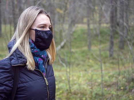 Beautiful european Women Wearing Protective Mask Outside Pretty young girl in medical black face mask in a forest. covid19 concept. modern reality. copy space. 2020, allergy. Autumn season. Copy space