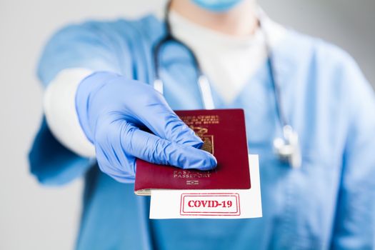 Doctor holding passport with COVID-19 sign stamped onto a white paper,immunity passport or risk-free certificate concept,recovered Coronavirus COVID19 patients being issued proof of convalescence, UK