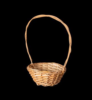 Wooden flower basket with a high handle made of twigs isolated on a black background.