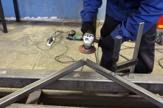 Grinding metal.Grinding wheel. Locksmith cleans iron corner after welding in workshop.