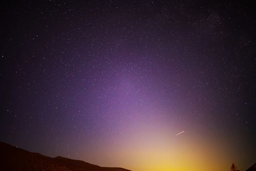 Starry sky at night in the Tyrolean Alps. Moonrise On a colorful sky, stars and comets. purple