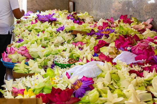 close-up Flowers in a Buddhist temple. Colorful flower offerings to Buddha inside temple of the sacred Bodhi Tree in Anuradhapura, Sri Lanka. The act of worship and a part of Buddhist praying ceremony