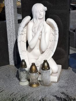Cemetery monument in the form of an angel of white in front of her are three lomads 06.04.2020 Kiev Ukraine