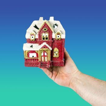 Hand holds toy house of red color. Concept of sale, purchase, rental or home insurance. Place for an inscription