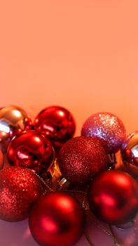 Collection of red Christmas balls on a pink festive background - vertical photo