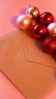 Envelope from craft paper with christmas red and pink balls on pink festive background - vertical photo