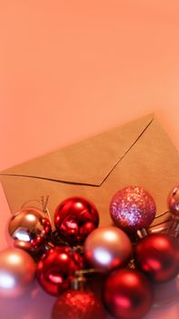 Envelope from craft paper with christmas red and pink balls on pink festive background - vertical photo