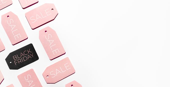 Top view on pattern of many pink and one black clothes tags on white background. Glamorous labels with copy space. Symbol of Black Friday sale and shopping. Flat lay.