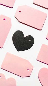 Top view on pattern of pink and black clothes tags in shape of heart on white background. Glamorous labels with copy space. Symbol of black Friday sale and shopping. Flat lay.
