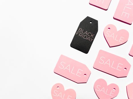 Top view on pattern of many pink and one black clothes tags on white background. Glamorous labels. Black Friday sale and shopping. Flat lay.