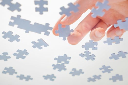 Assembling Jigsaw Puzzle. Hand Connect the Pieces of a Jigsaw Puzzle. Leisure Activity. Playing Calm Board Game. Pastime, a Hobby. Unfinished Puzzle. Finding a Solution. Bottom View. White Background