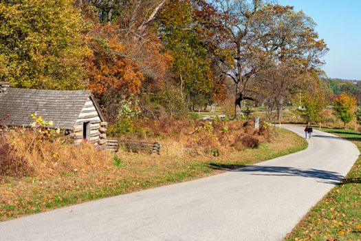 A Small Road with a Log Cabin and a Couple Walking Down It at Valley Forge National Historical Park