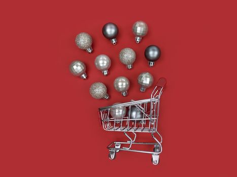 Supermarket trolley and Christmas tree baubles on red paper.